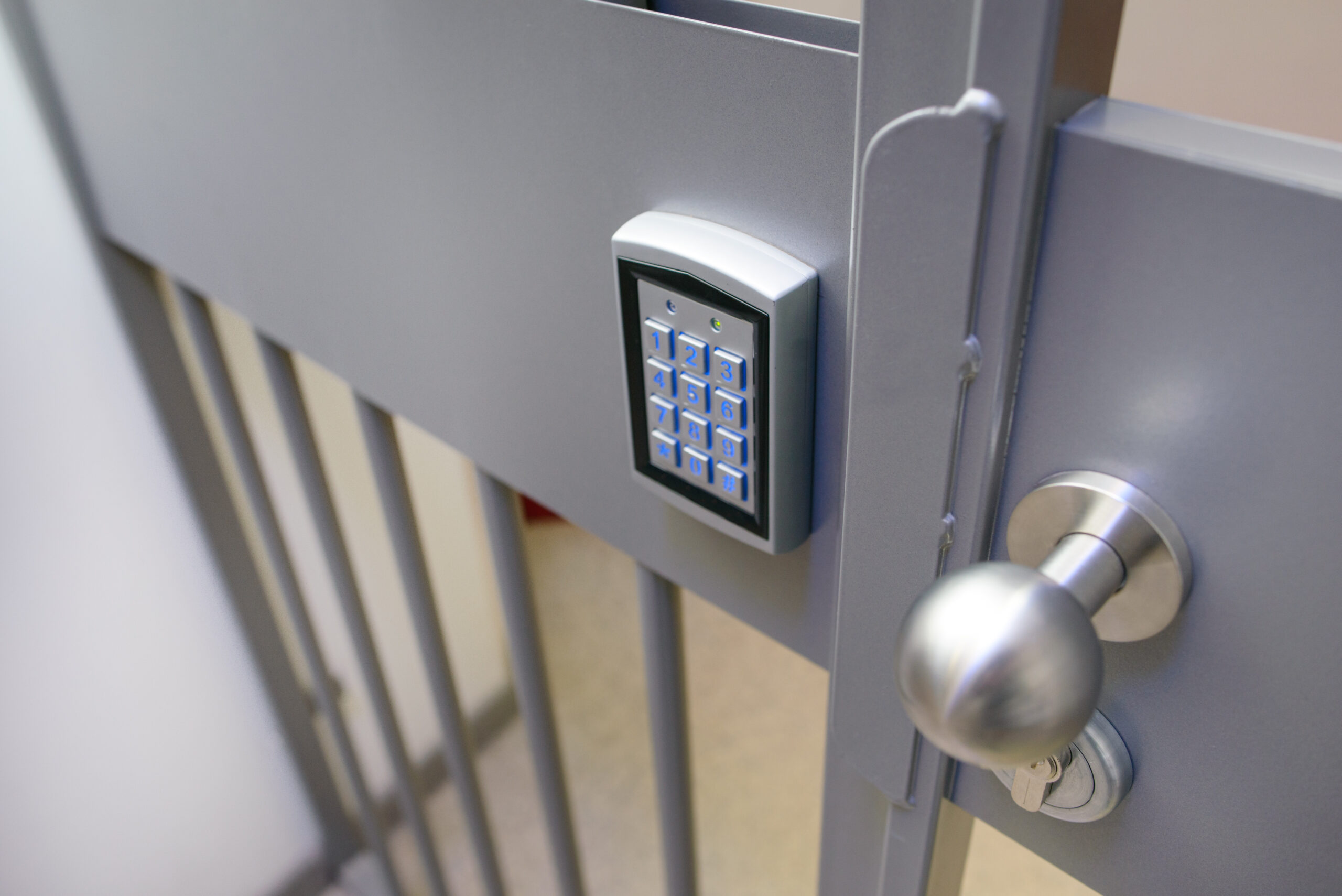 Closeup of electronic lock with keypad  and steel bobble handle on metal bar security door