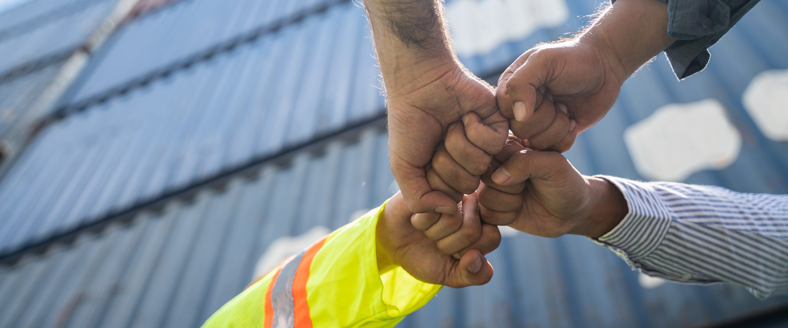 Unity and success concept.Bottom view of Engineer team people st Unity and success concept.Bottom view of Engineer team people standing hands holding together at the container yard.Low Angle View of worker and businessman Team Stacking Hands.Panoramic banner.